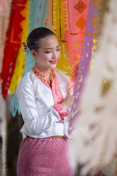Fototapeta Woman in traditional attire smiles while surrounded by colorful, decorative flags, creating festive and cultural atmosphere