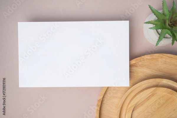 Fototapeta Empty white blank greeting or invitation card, cactus, wooden plate on beige background. Mock up presentation.