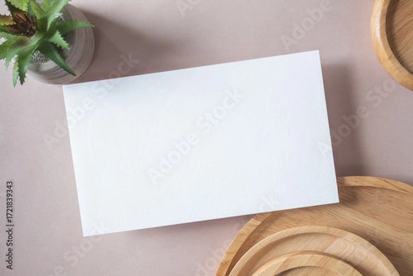 Fototapeta Empty white blank greeting or invitation card, cactus, wooden plate on beige background. Mock up presentation.