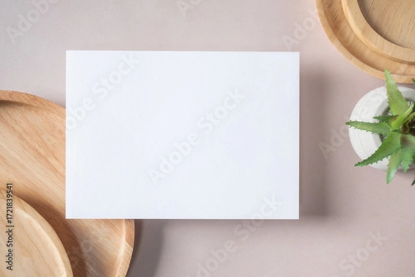 Fototapeta Empty white blank greeting or invitation card, cactus, wooden plate on beige background. Mock up presentation.