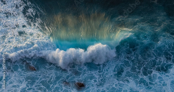 Fototapeta Big ocean wave breaking on the beach at sunset. White seagull soaring over the wave. Atlantic ocean in Nazare, Portugal. 