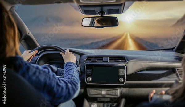 Fototapeta Close-up of female hands on the steering wheel while driving car. Snowy winter road visible through the windshield. Transportation, travel and journey forward on  frosty day.