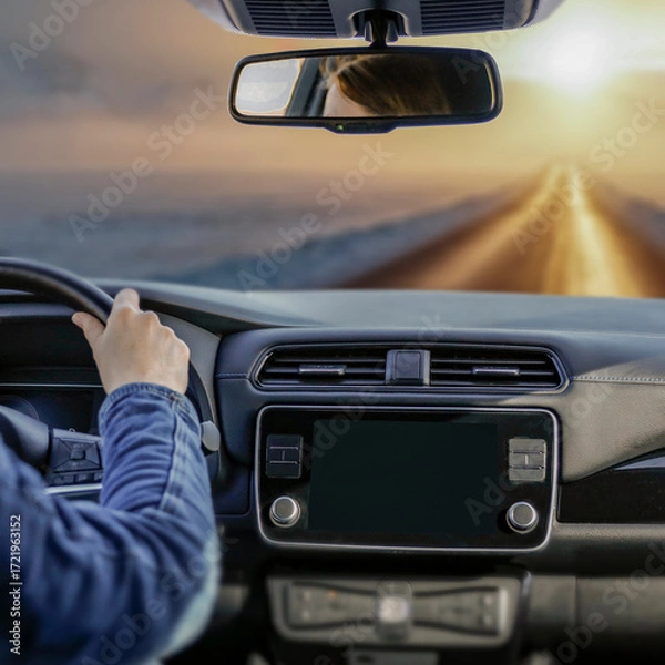 Fototapeta Close-up of female hands on the steering wheel while driving car. Snowy winter road visible through the windshield. Transportation, travel and journey forward on  frosty day.