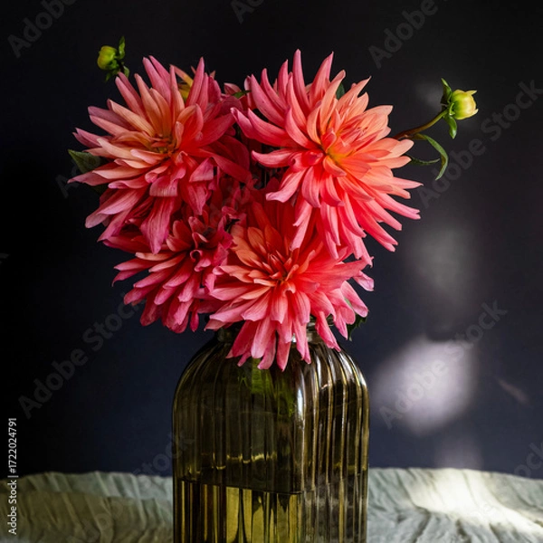 Fototapeta Bouquet of dahlias in green glass vase on dark background with sunlight.Vase of autumn flowers stands on table.Concept: greeting card, autumn holidays. Selective focus. Square