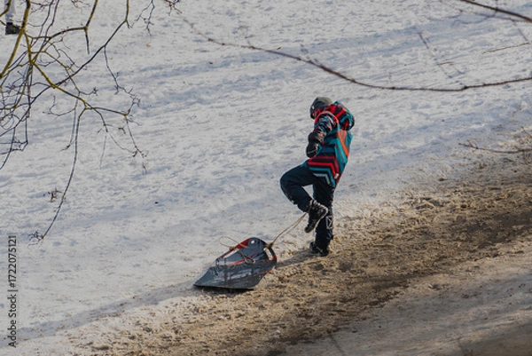 Obraz A boy plays with his snowboard in the park on a winter day
