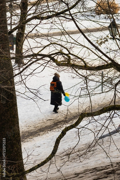 Obraz branches of a dry tree in the foreground and in the distance, a woman wrapped up in a coat walks with colorful balloons in her hand