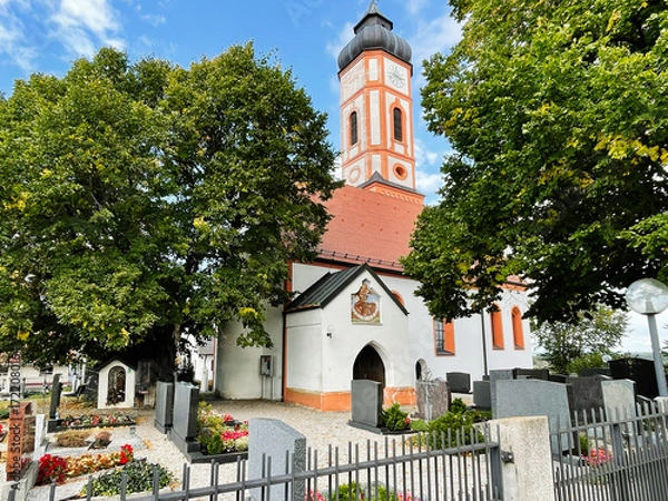 Fototapeta Historic church St. Sebastian Puch in Furstenfeldbruck, Germany with clock tower and lush cemetery surrounding the building