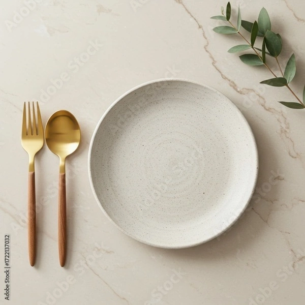 Fototapeta A rustic speckled plate with gold cutlery and eucalyptus sprig isolated on white background
