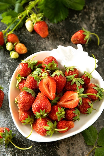 Fototapeta Fresh summer strawberries in white bowl on dark rustic surface.
