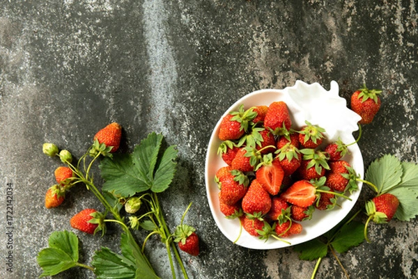 Fototapeta Fresh summer strawberries in white bowl on dark rustic surface.