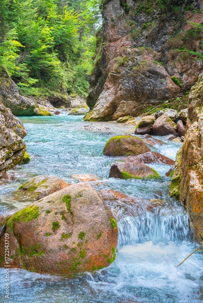 Fototapeta Turquoise river winding through mossy rocks in a forest canyon with cascading clear water