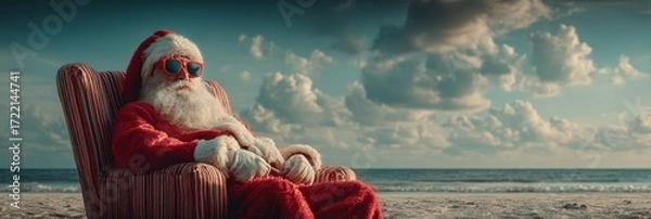 Fototapeta Santa relaxing on a beach in festive attire during holiday season under a bright sky