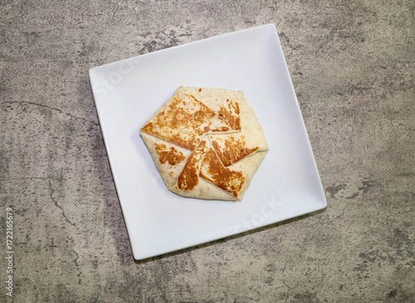 Fototapeta Crunchy wrap made with flour tortilla, a crunchy tostada inside topped seasoned ground beef, lettuce, tomato, cheese and sour cream inside and toasted on the griddle.