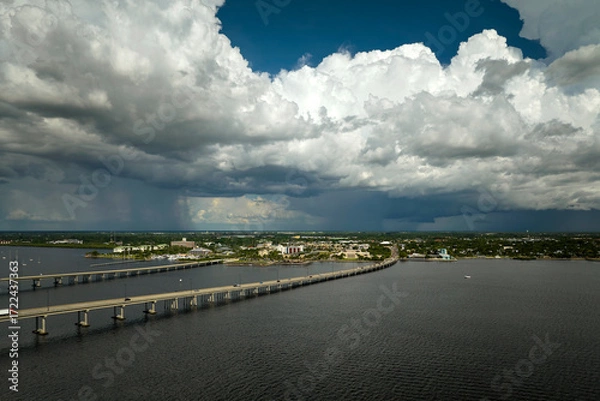 Fototapeta Heavy thunderstorm approaching traffic bridge connecting Punta Gorda and Port Charlotte over Peace River. Bad weather conditions for driving during rainy season in Florida