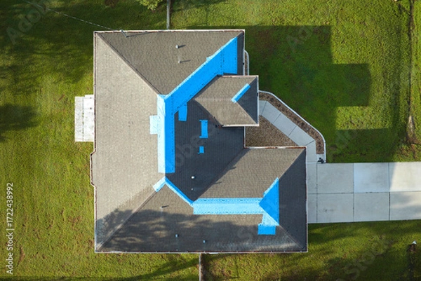 Fototapeta Top view of leaking house roof covered with protective tarp sheets against rain water leaks until replacement of asphalt shingles. Damage of building rooftop as aftermath of hurricane Ian in Florida