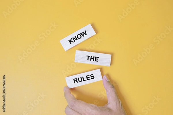 Fototapeta Know the rules symbol. Wooden blocks with words Know the rules. Beautiful orange background. Businessman hand. Business and Know the rules concept