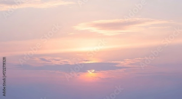Obraz A serene sunset with a soft pink and orange sky, scattered clouds, and a distant sun setting behind a mountain range.
