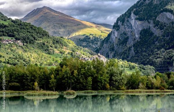 Fototapeta mountain lake in mountainous landscape bordered by forest under cloudy sky in french alps