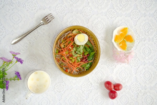 Obraz Close-up of rice noodles on a white lace background, eggs, carrots, top view