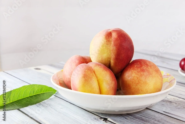 Obraz Close-up of peaches, peach leaves, sweet fruits in a plate on wooden table