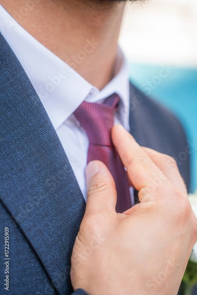 Obraz Man in a suit fixing his tie.