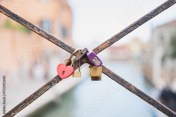 Fototapeta Colorful locks of love hanging on a bridge over a canal in Venice, Italy, showcasing romantic sentiments and beautiful craftsmanship