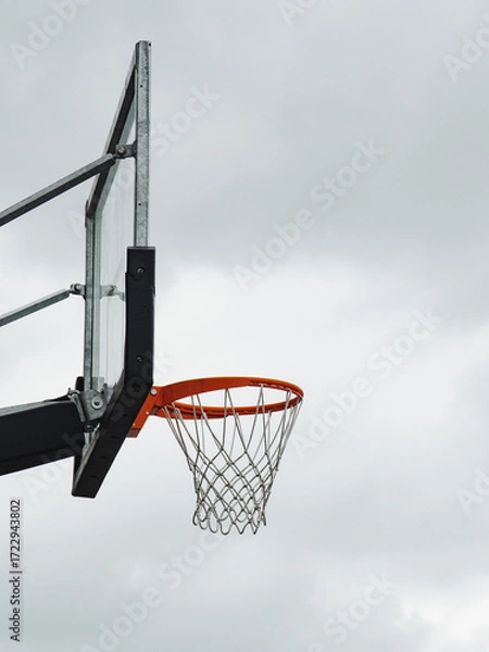 Fototapeta Basketball hoop positioned against a cloudy sky during the late afternoon in a public park