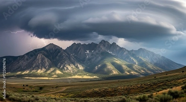 Fototapeta Dramatic Storm Clouds Looming Over a Sunlit Mountain Range.