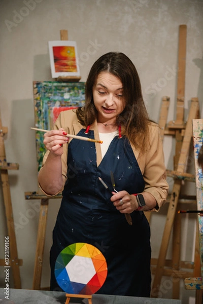 Fototapeta  Teacher learn children to draw pictures in an art lesson. Artist explains how to mix and combine colors. Childs painting in workshop. Kids drawing brush on easel. Education, learning concept.