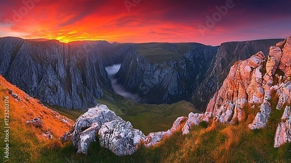 Fototapeta Mountain peaks glowing under sunrise sky, mist floating through valley