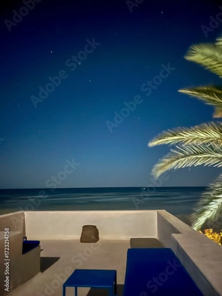 Fototapeta A serene scene unfolds on the roof of a white house in Djerba, Tunisia where stars twinkle brightly in the clear night sky, creating a tranquil ambiance.