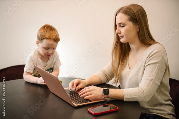 Fototapeta Homeschooling and freelance job. Child make noise and disturb woman work. Mother working from home with kid. Quarantine and closed nursery school. Distance learning through war. Stay at home.