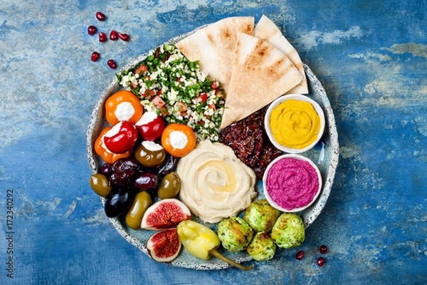 Fototapeta Bliski wschód meze z zielonym falafelem, pita, suszone pomidory, dynia i hummus buraków, oliwki, nadziewana papryka, tabbouleh, fig. Pomysł na imprezę z przystawką śródziemnomorską