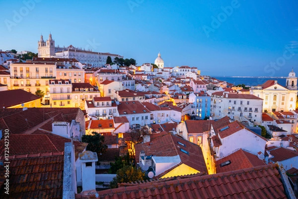 Fototapeta Panoramic Night View Over Alfama’s Rooftops and Tagus River from Miradouro da Graca Viewpoint in Lisbon, Portugal