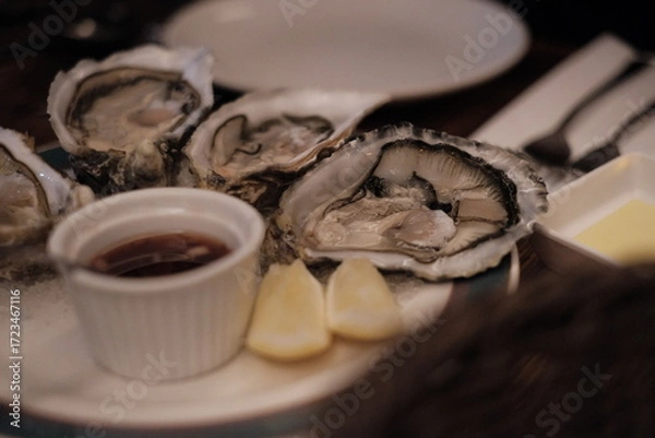 Fototapeta Fresh oysters with lemon and ice on wooden table, closeup stock photo