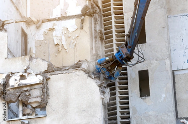 Fototapeta Demolition of multi-story building using heavy machinery and special equipment. Construction site with concrete destruction, industrial renovation, and urban dismantling process.