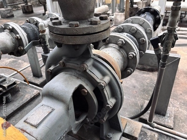 Fototapeta An up-close, detailed view of industrial pipes, pumps, and valves, highlighting the complex network of machinery in a factory or plant setting.