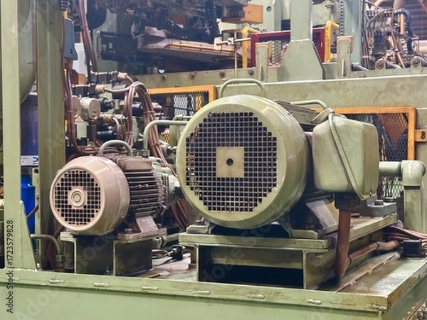 Fototapeta A close-up view of two large industrial electric motors on a machine in a manufacturing factory, with a muted, industrial color palette.