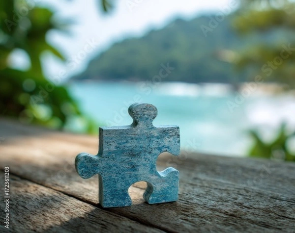 Fototapeta A single light blue jigsaw puzzle piece sits on a weathered wooden surface, blurred tropical scenery in the background
