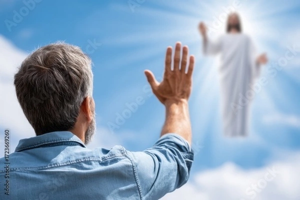 Fototapeta A rear view of a gray-haired person reaching toward a radiant, blurred figure of Jesus in the bright blue sky.