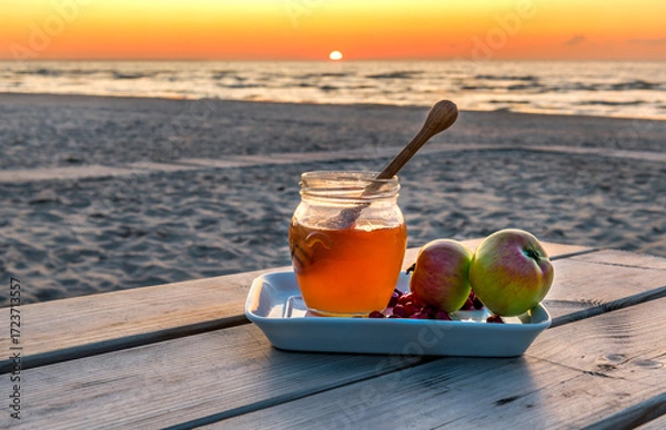Obraz Festive food, background with blurred sun, sand e beach and waving  sea. Honey and apple are traditional food attributes for Jewish New Year holiday - Rosh Hashanah
