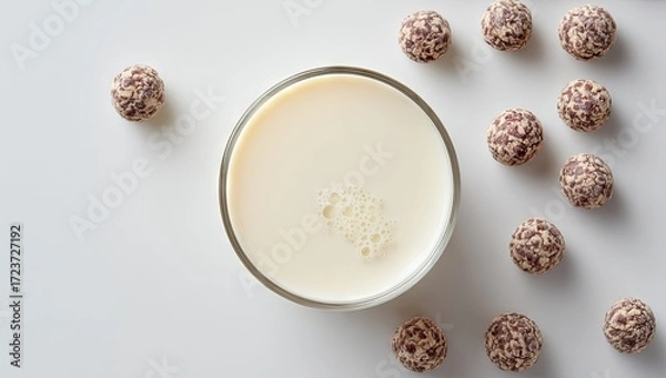 Obraz Top view of a creamy beverage in a glass surrounded by sweet chocolate truffle balls on a white background.