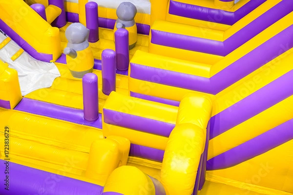 Fototapeta Inflatable jumping castle or bounce house with colorful slide and playground equipment inside of department store, high angle view with copy space