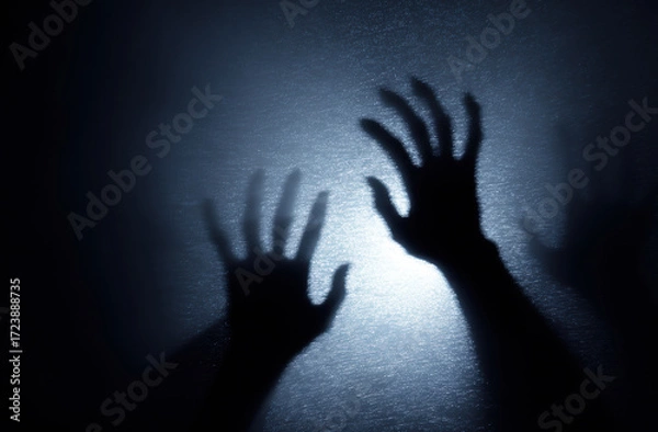 Fototapeta Silhouetted hands reaching out against textured, illuminated background create mysterious and eerie atmosphere