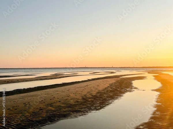 Fototapeta As the sun sets over Plage Peirere in Arcachon, golden rays reflect on the wet sand, creating a peaceful and tranquil atmosphere perfect for a calming beach walk.