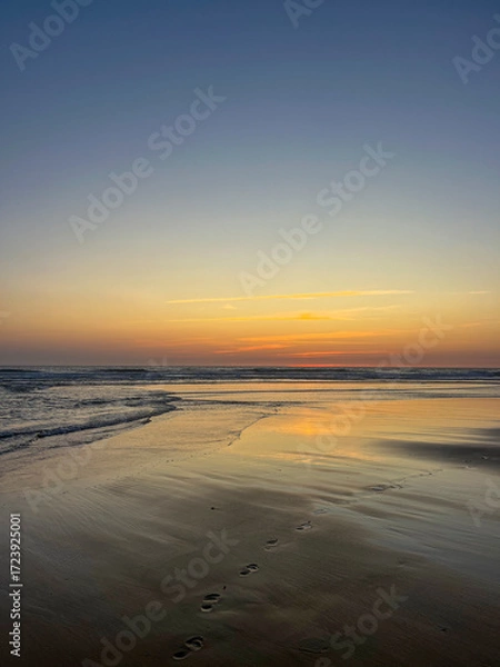 Fototapeta Beautiful sunset illuminates the sky above Biscarosse beach. The calm sea reflects the vibrant colors, creating a serene atmosphere perfect for relaxation at dusk.