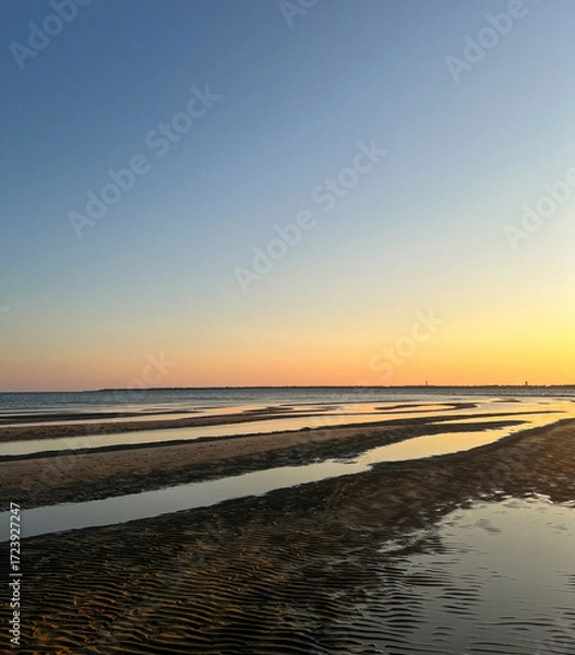 Fototapeta As the sun sets over Plage Peirere in Arcachon, golden rays reflect on the wet sand, creating a peaceful and tranquil atmosphere perfect for a calming beach walk.