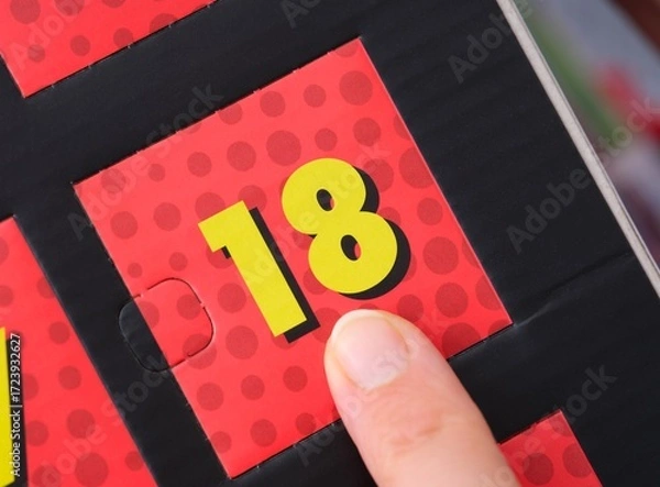 Fototapeta Woman finger pointing at the number 18 on an advent calendar.