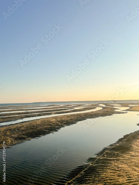 Fototapeta As the sun sets over Plage Peirere in Arcachon, golden rays reflect on the wet sand, creating a peaceful and tranquil atmosphere perfect for a calming beach walk.