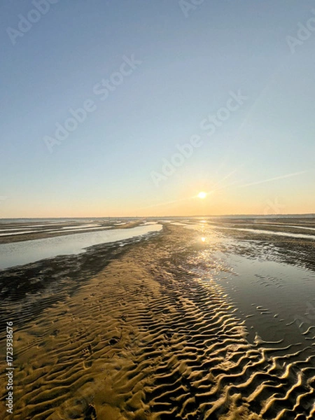 Fototapeta As the sun sets over Plage Peirere in Arcachon, golden rays reflect on the wet sand, creating a peaceful and tranquil atmosphere perfect for a calming beach walk.
